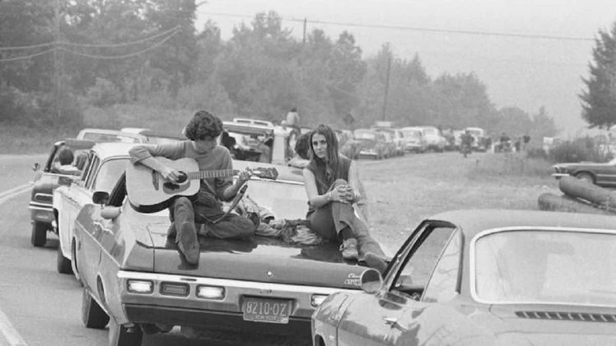 μποτιλιαρισμένα αυτοκίνητα και ένας άνδρας παίζει κιθάρα πάνω στο αυτοκίνητό του για να περάσει η ώρα