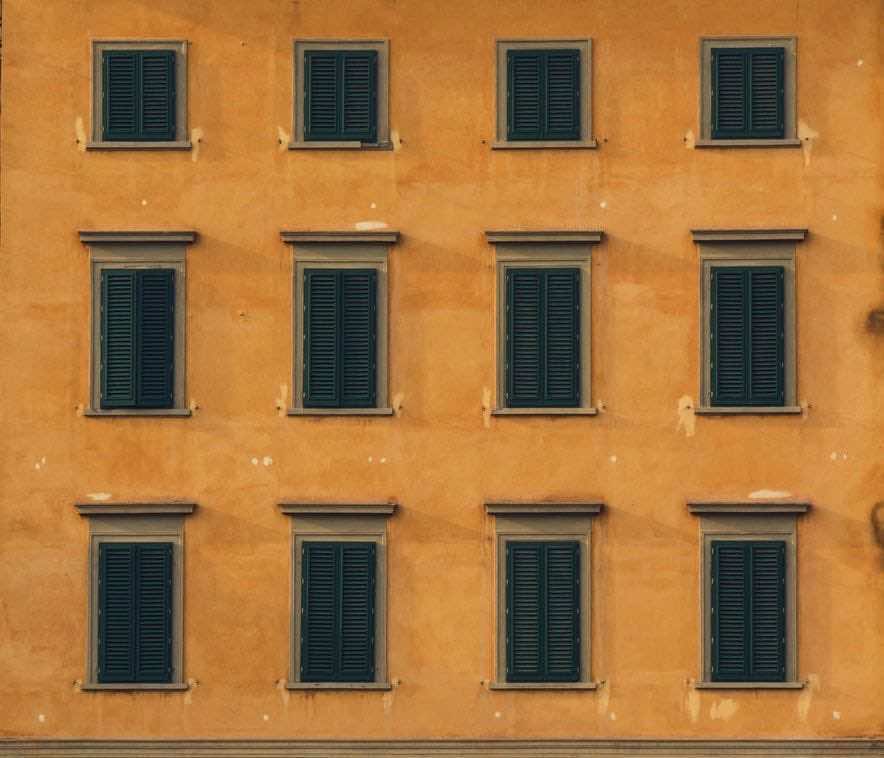 Πορτοκαλί πρόσοψη κτιρίου με κλειστά παντζούρια