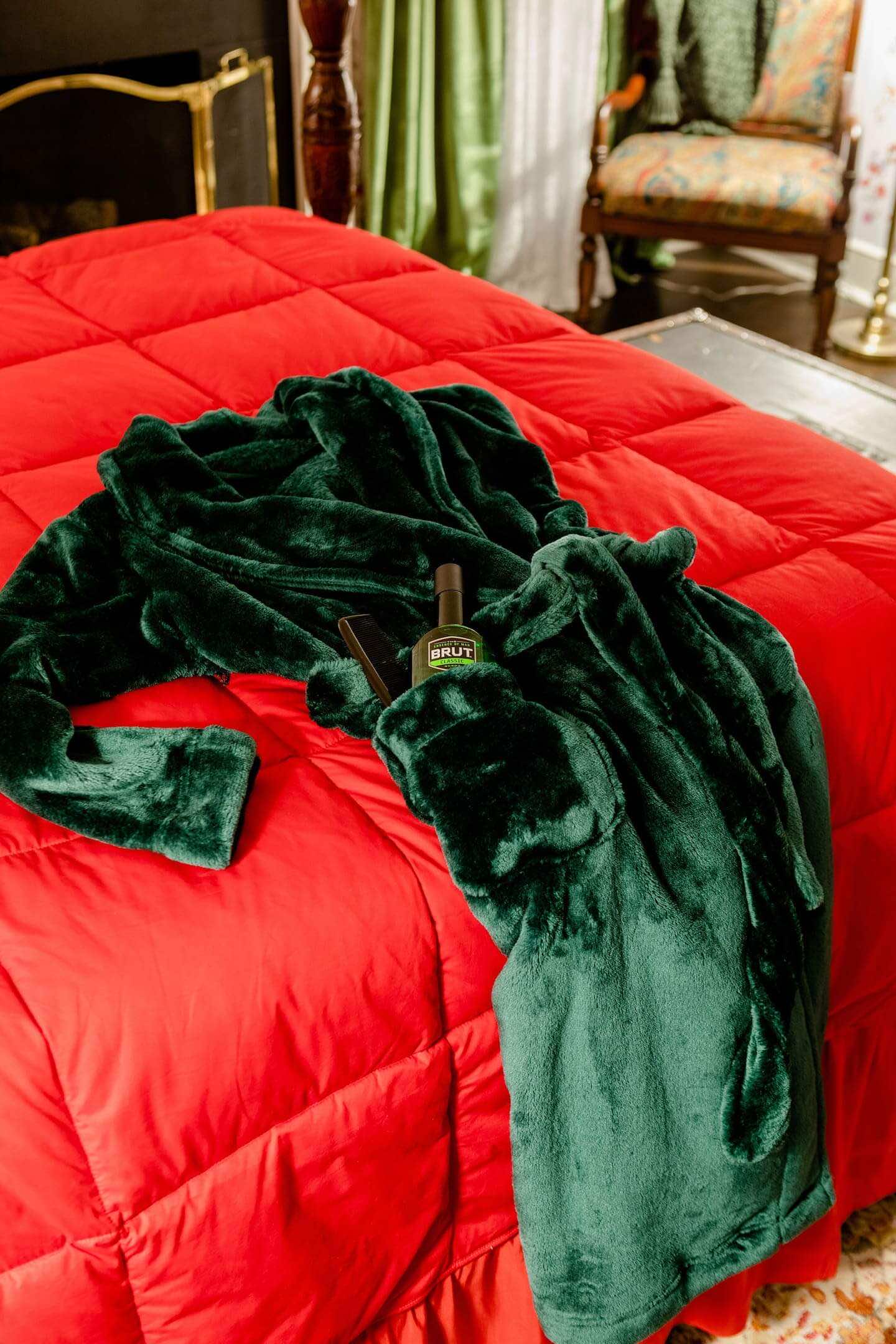 κρεβάτι με κόκκινο πάπλωμα και ποράσινη ρόμπα ακουμπισμένη πάνω