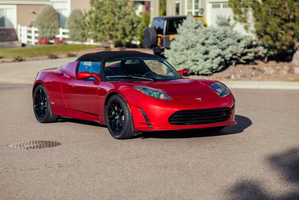 κόκκινο αυτοκίνητο μάρκας Tesla Roadster σταματημένο σε δρόμο