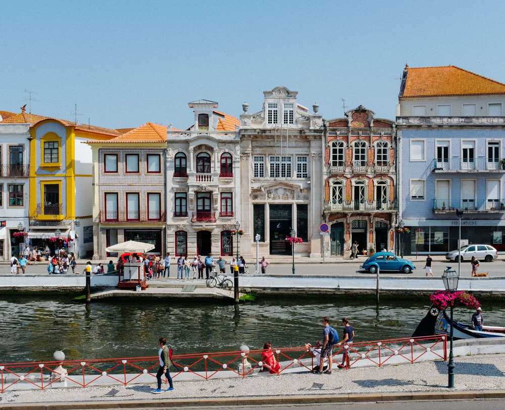 Εικόνα από την Πορτογαλία, ποπλύχρωμα σπίτια στις όχθες ποταμού και κόσμος που περπατάει