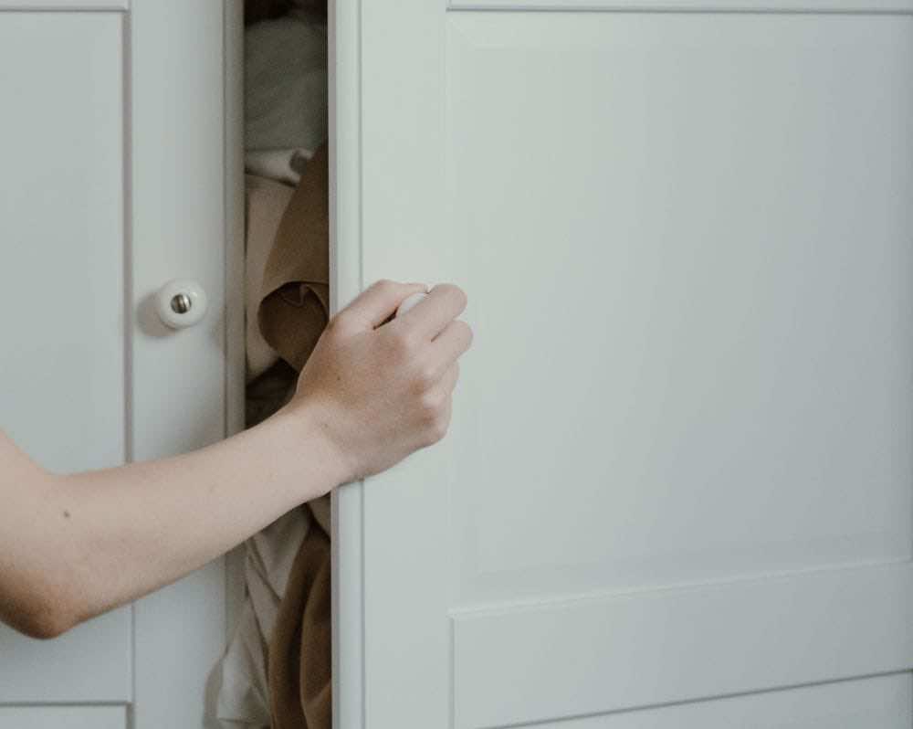 Χέρι ανοίγει την πόρτα λευκής ντουλάπας