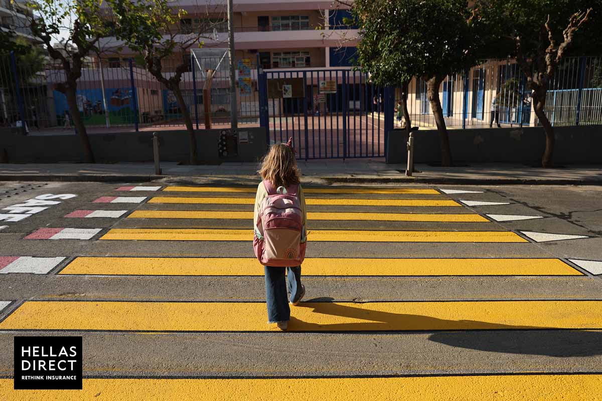 κορίτσι διασχίζει κίτρινη διάβαση που καταλήγει σε σχολείο, το βλέπουμε πλάτη