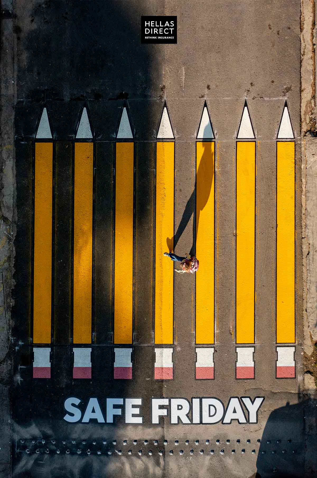 Εικόνα από ψηλά, διάβαση με κίτρινα μολύβια με ένα κορίτσι να τη διασχίζει. Στην άσφαλτο γράφει: Safe Friday