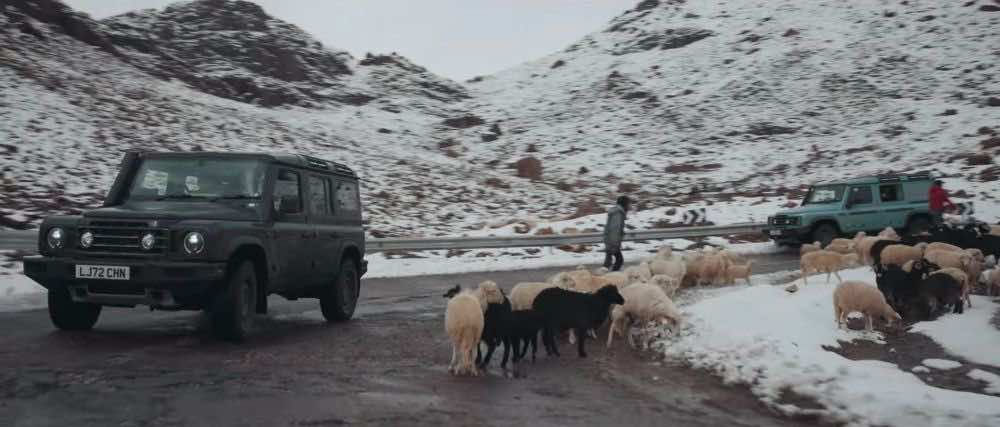 Τζιπ εν κινήσει σε δρόμο με χιόνια κι ένα κοπάδι πρόβατα να τον διασχίζει