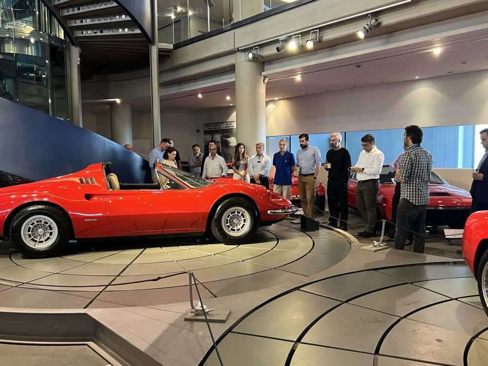 Ξενάγηση στο Ελληνικό Μουσείο Αυτοκινήτου, κόκκινο αυτοκίνητο αντίκα και όρθιος κόσμος παρακολουθεί