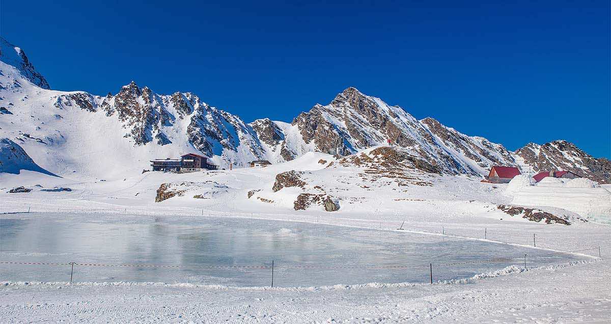 αλπκό τοπίο με χιόνια, βουνά και παγωμένη λίμνη