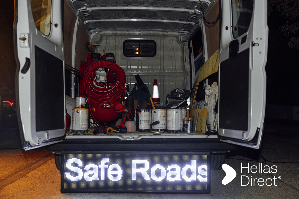Το van του Safe Roads project από πίσω με ανοιχτή πόρτα, γεμάτομπογιές και εργαλεία
