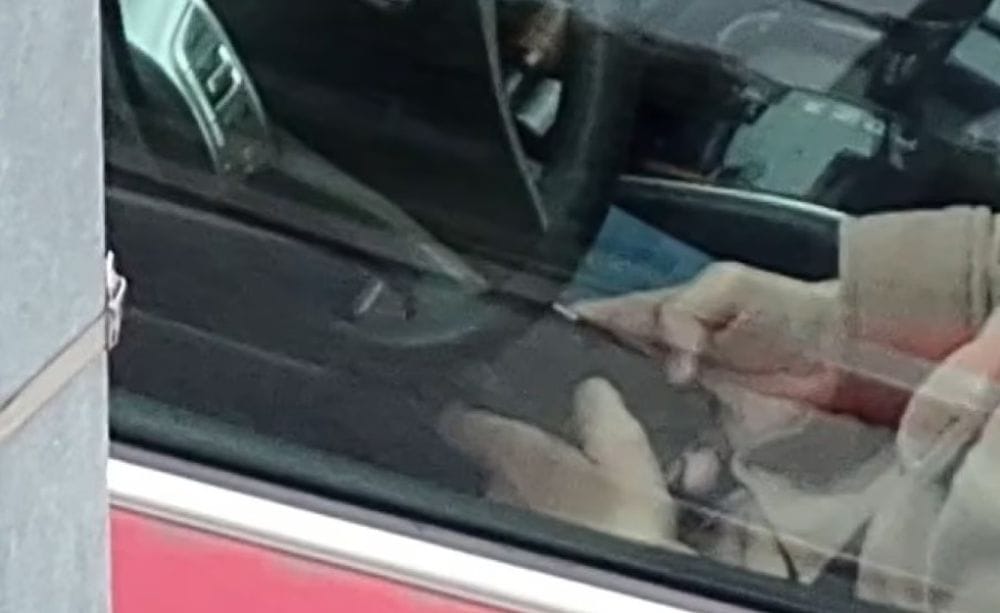 οδηγός με το τιμόνι μπροστά του και τα δύο χέρια του στο κινητό του πάνω στα πόδια του