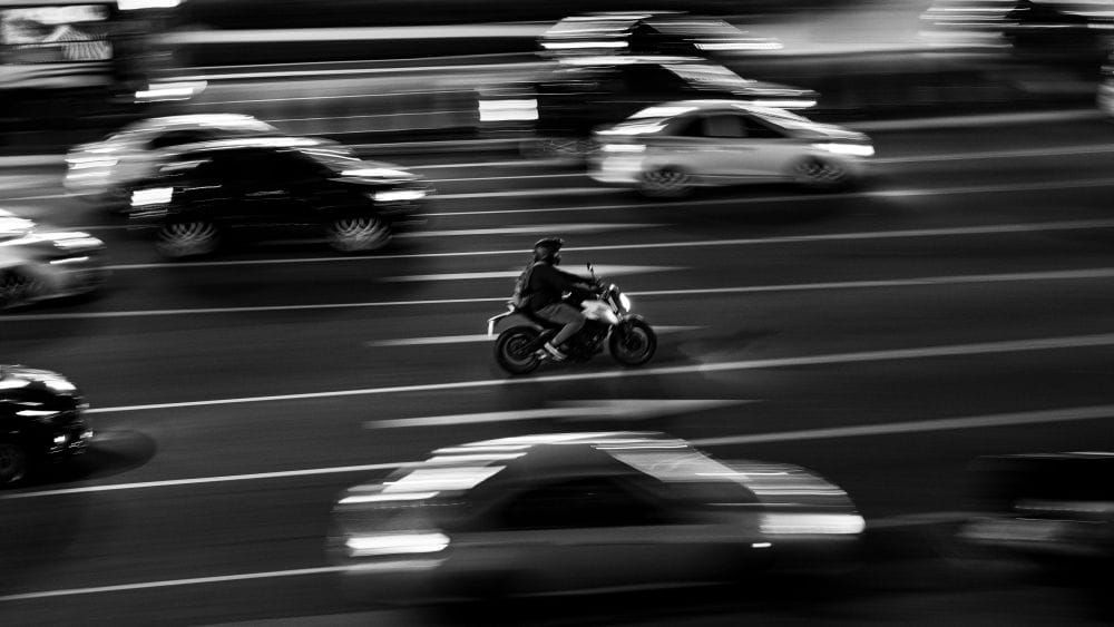 θολή ασπρόμαυρη εικόνα δρόμου με κίνηση, αυτοκίνητα και μηχανή