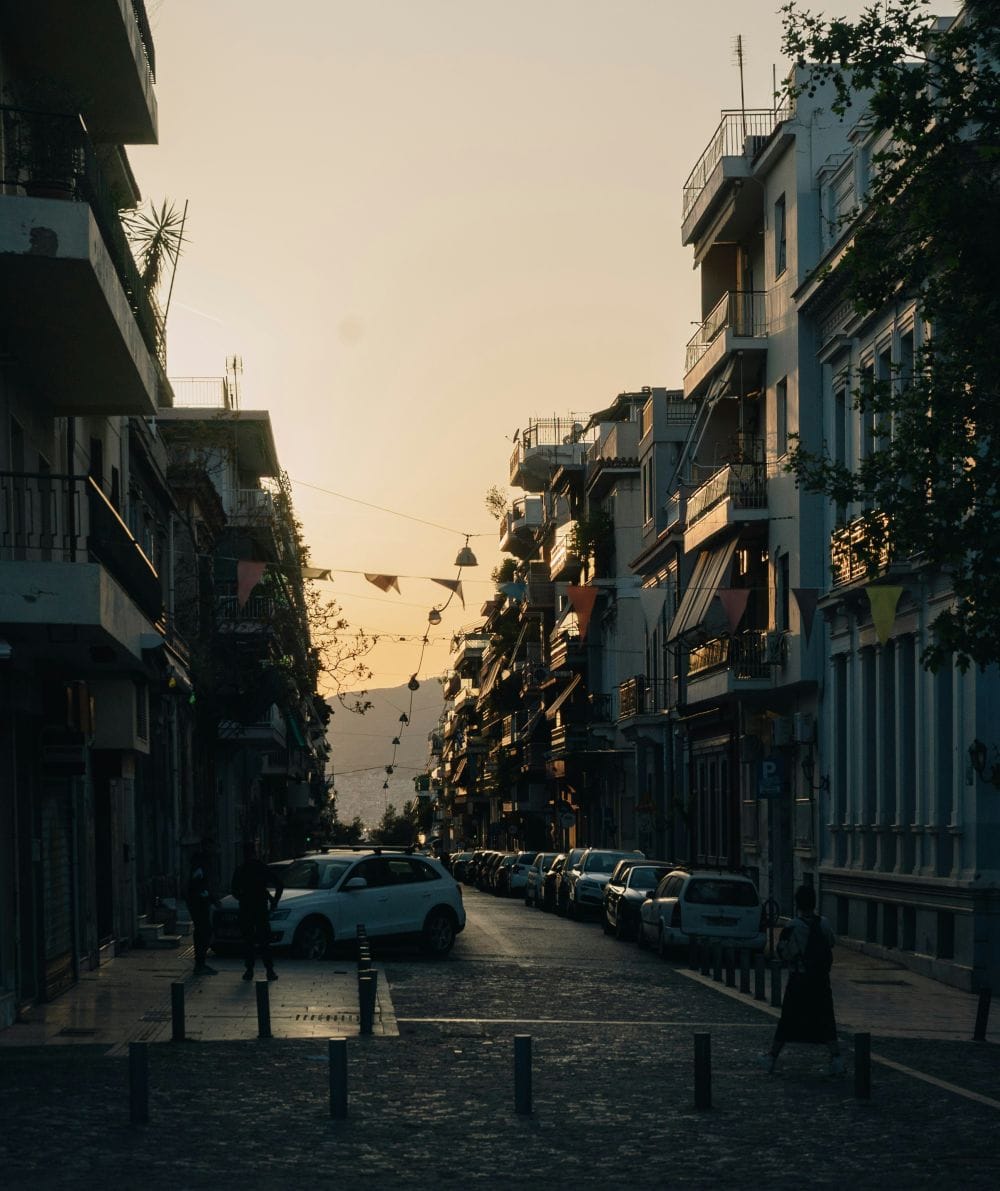 δρόμος πόλης σούρουπο, παρκαριμένα αυτοκίνητα, δεξιά κι αριστερά ψηλά κτήρια