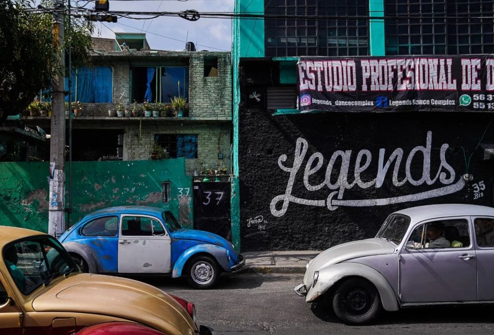 τρεις Σκαραβαίοι σε δρόμο, στο φόντο σπίτια με γκράφιτι