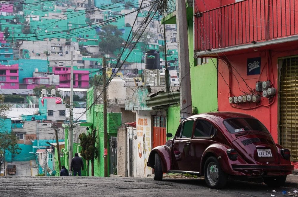 σκαραβαίος παρκαρισμένος σε δρόμο, στο φόντο λόφος με χρωματιστά σπίτια