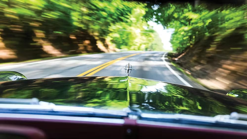 μαύρο Continental Mark II εν κινήσει, δεξιά κι αριστερά δέντρα