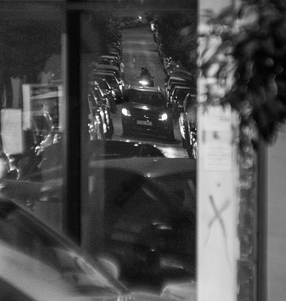 ασπρόμαυρη εικόνα αυτοκινήτου με αναμμένα φώτα μέσα από τζάμι για την καλύτερη ασφάλεια αυτοκινήτου 