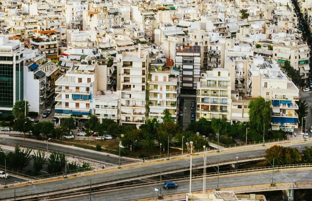 δρόμος με αυτοκίνητο από ψηλά, στο φόντο πολυκατοικίες, για το θέμα διασταυρωτικοί έλεγχοι οχημάτων