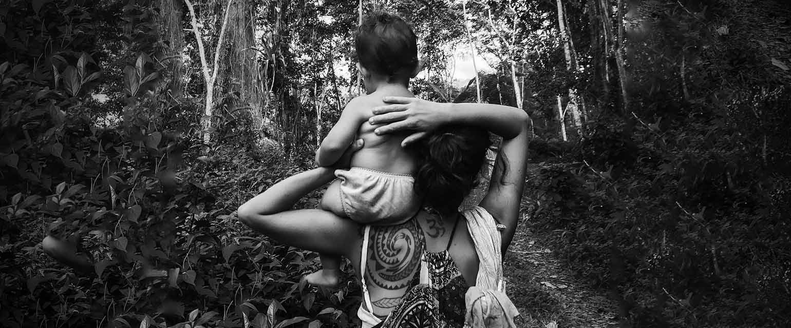 Μητέρα με μωρό στον ώμο από πίσω με φόντο δάσος