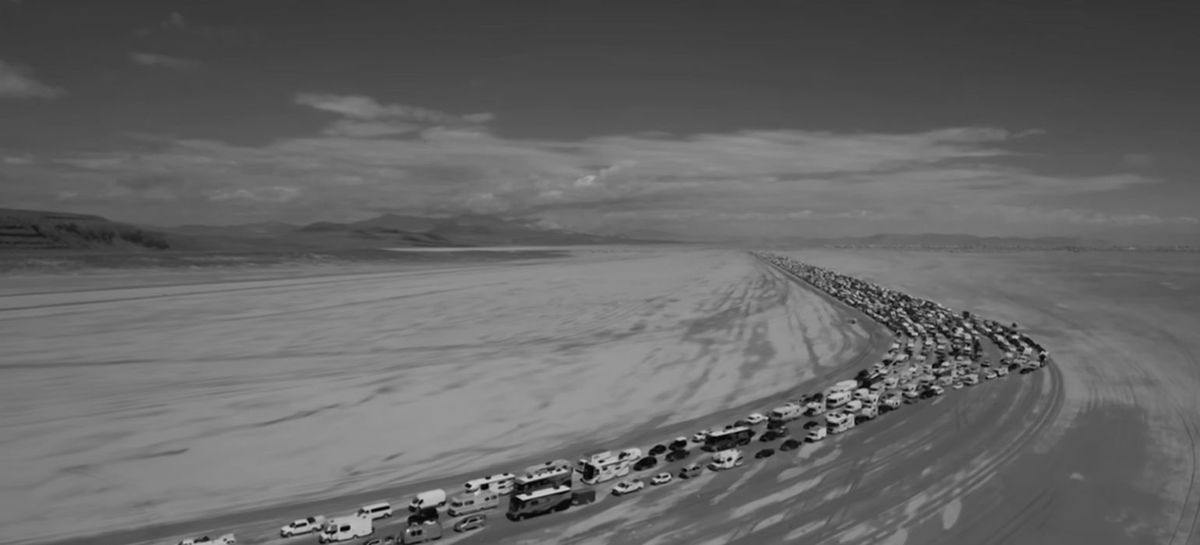 ασπρόμαυρη εικόνα με τεράστια ουρά αυτοκινήτων μέσα στην έρημο της Νεβάδα