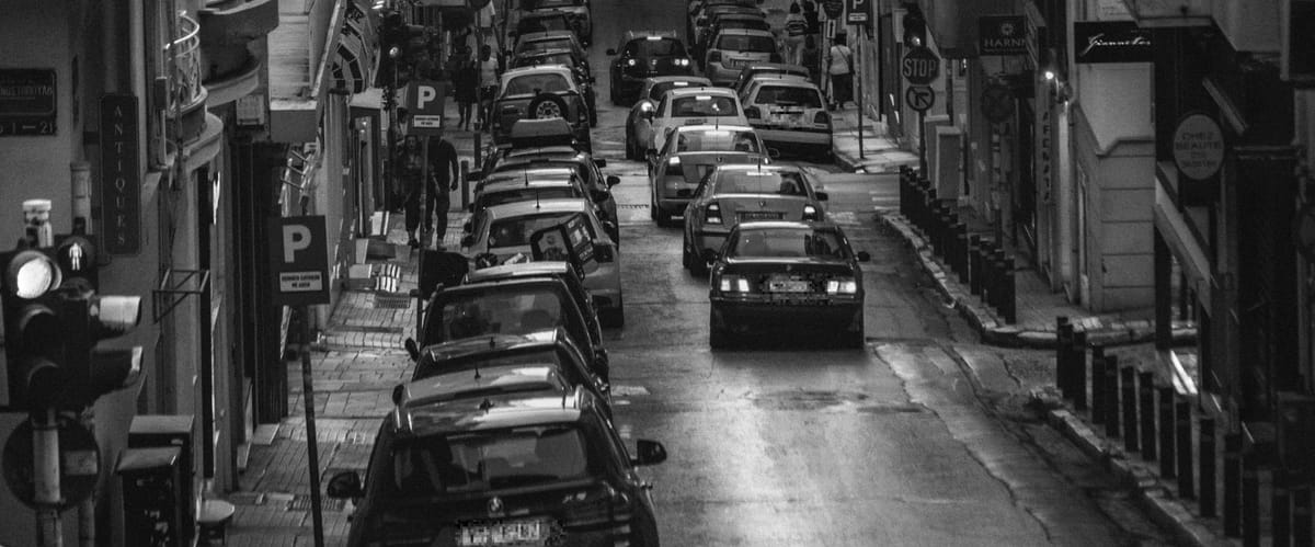 ασπρόμαυρη εικόνα, δρόμος από την άκρη του με αυτοκίνητα εν κινήσει και παρκαρισμένα