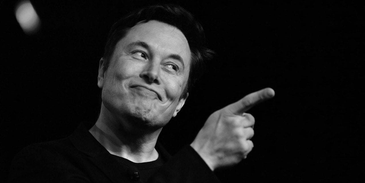 ασπρόμαυρη εικόνα, ο Elon Musk με υψωμένο δάκτυλο σε μαύρο φόντο