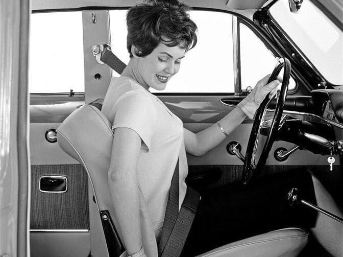 ασπρόμαυρη εικόνα vintage, γυναίκα οδηγός στη θέση του οδηγού αυοτκινήτου βάζει τη ζώνη της