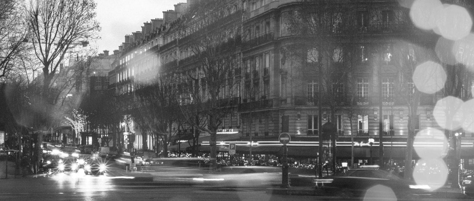 ασπρόμαυρη εικόνα, δρόμος στο Παρίσι, στο φόντο κτίρια και καφέ, αυτοκίνητα ανφάς με αναμμένα φώτα