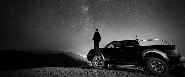Οδηγός έξω από το αυτοκίνητό του κοιτά τον νυχτερινό ουρανό γεμάτο αστέρια
