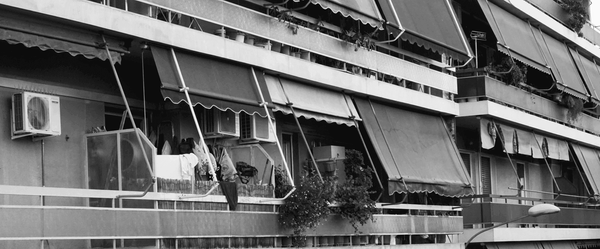 ασπρόμαυρη εικόνα, πρόσοψη πολυκατοικίας μπαλκόνια με τέντες