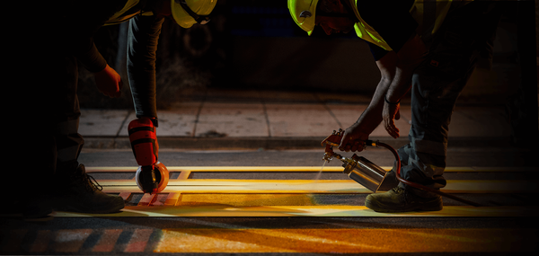 Νύχτα, εργάτες σκυμμένοι στην άσφαλτο βάφουν διάβαση πεζών με κίτρινο χρώμα
