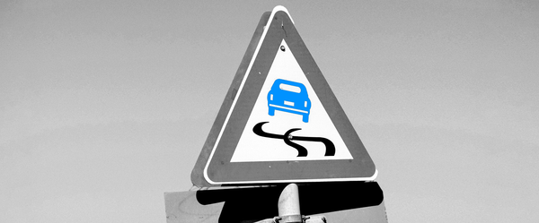ασπρόμαυρη τριγωνική εικόνα με πινακίδα για επικίνδυνο δρόμο, μπλε το αυτοκίνητο μέσα της